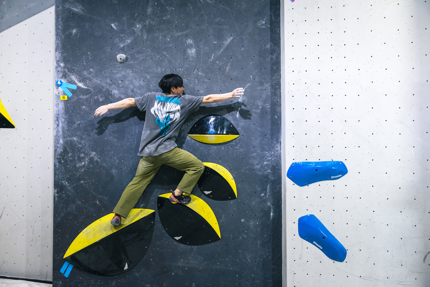 Person climbing on an indoor rock climbing wall with colorful holds.